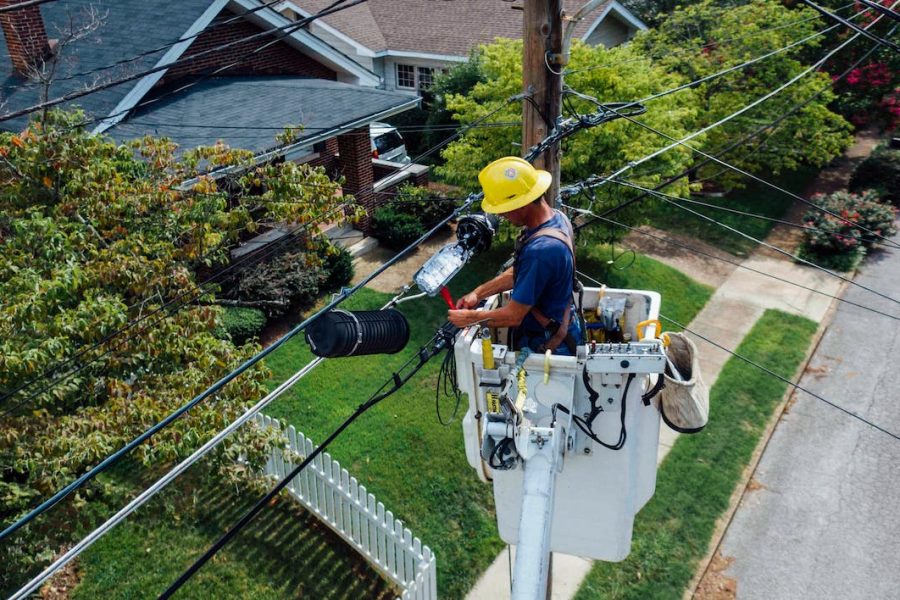 electrical utility employee in cherry picker repairing electrical wiring connection