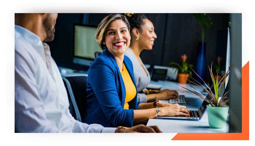 three smiling employees working on laptops