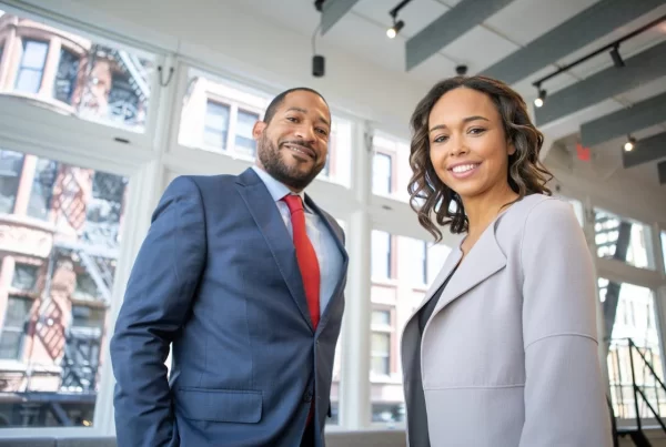 man and woman in business attire smiling at camera