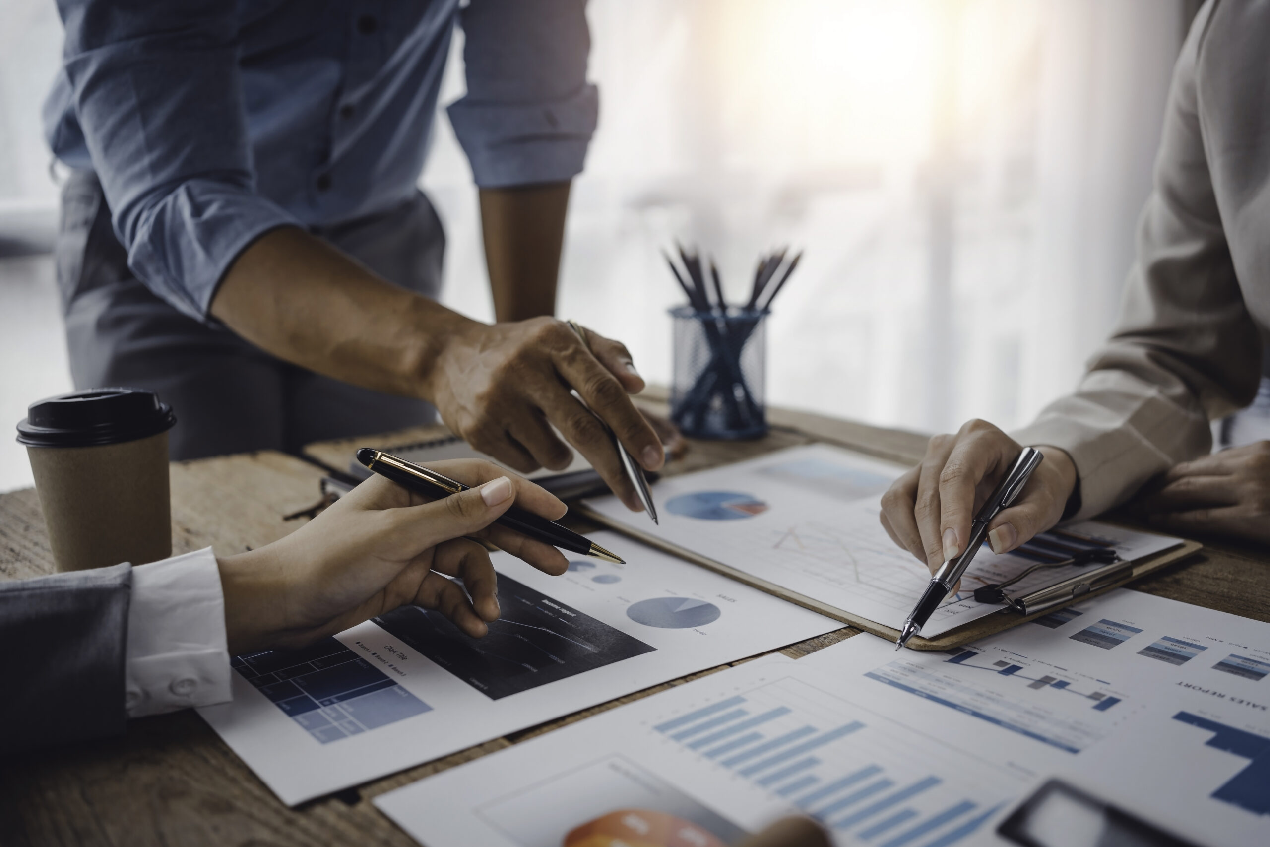 Business people pointing to a graph to analyze market data Net profit balance sheet to plan new marketing strategies to extend existing products. The Dunvegan Group examining financial data